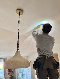 Electrician installing a hanging light fixture